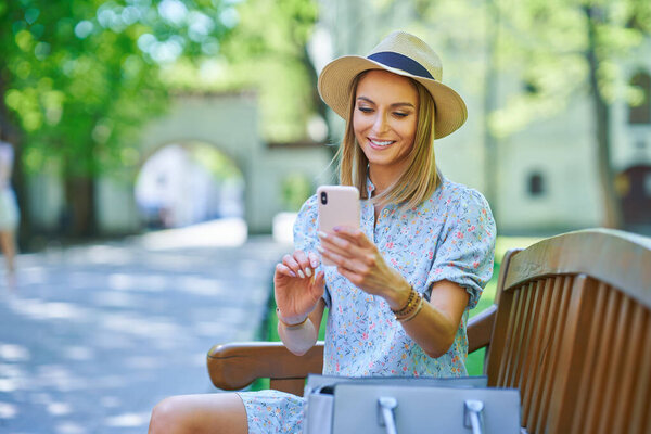 A girl sitting on a bench with smartphone