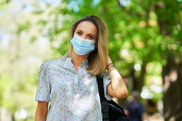 Young woman in the mask walking outdoor — Stock Photo, Image