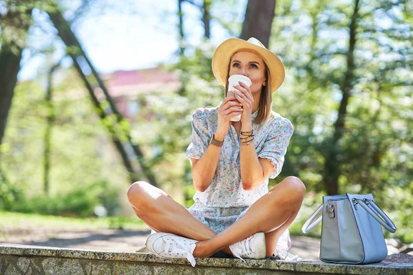 Жінка в капелюсі з кавою розслабляється — стокове фото
