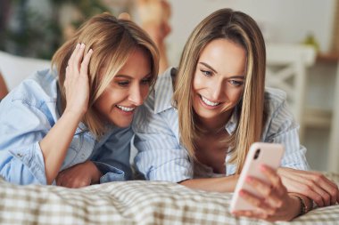 Yatakta selfie çeken iki genç kız arkadaş.