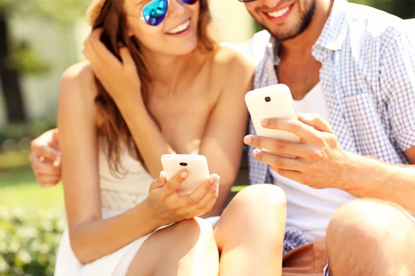 Pareja feliz usando smartphones — Foto de Stock