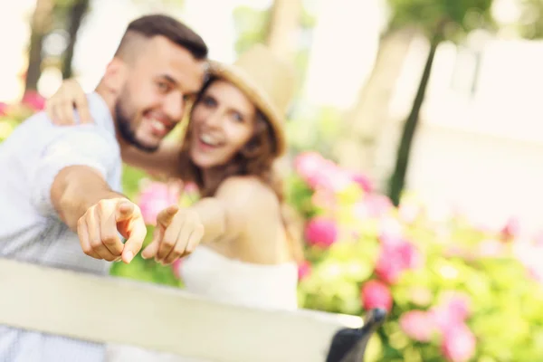 Casal no parque apontando para a câmera — Fotografia de Stock