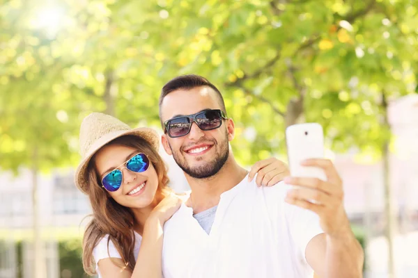 Lyckliga paret tar selfie i parken — Stockfoto