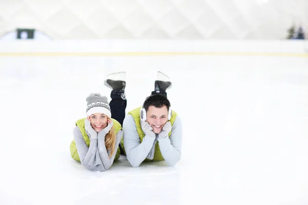 Casal alegre deitado na pista de patinação — Fotografia de Stock