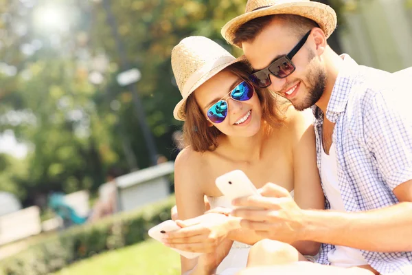 Koppel met smartphones in het park — Stockfoto