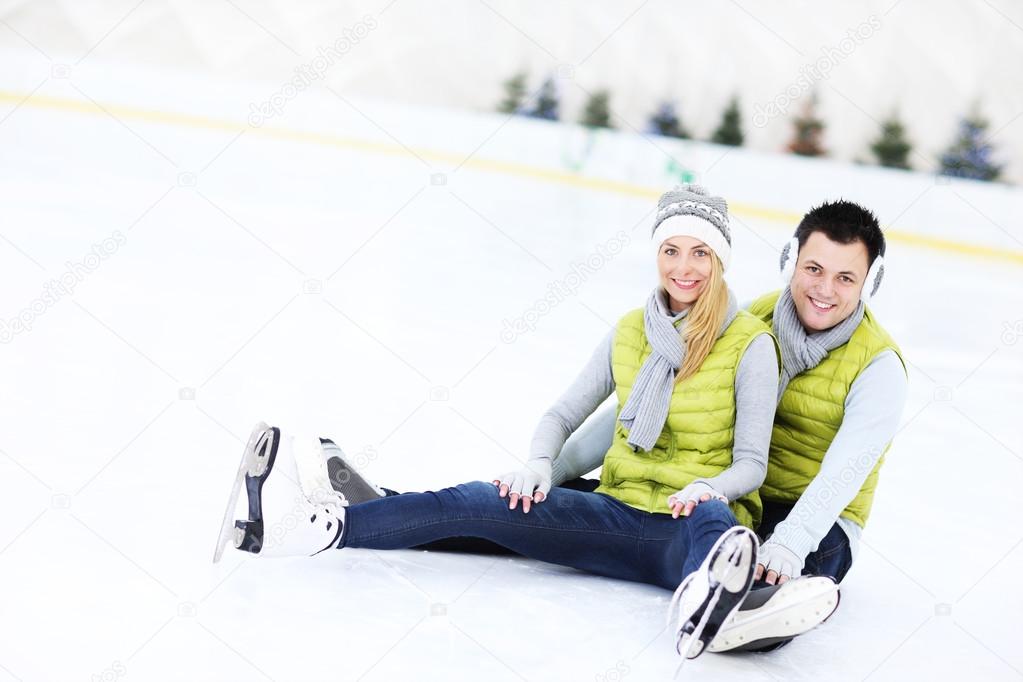 Cheerful couple sitting on the skating rink