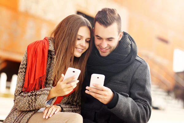 Romantisch paar met behulp van slimme telefoons in de herfst van lopen — Stockfoto