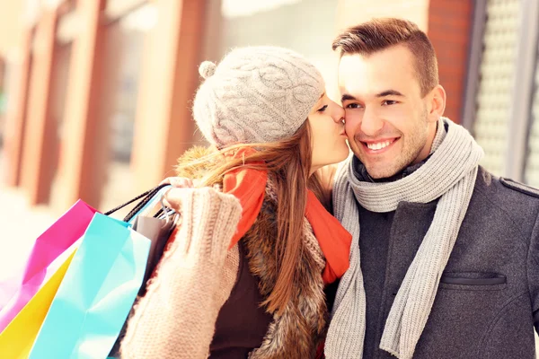 Lycklig kvinna kysser en man medan shopping — Stockfoto