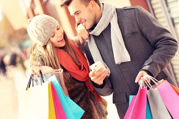 Pareja alegre de compras en la ciudad con smartphone — Foto de Stock