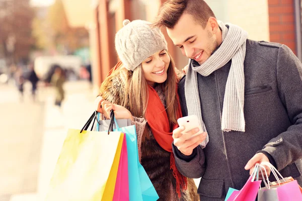 Casal feliz compras na cidade com smartphone Imagens De Bancos De Imagens