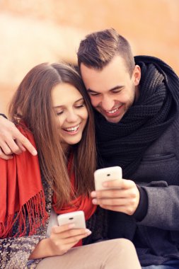 Çift bir bankta oturan ve akıllı telefonlar kullanma