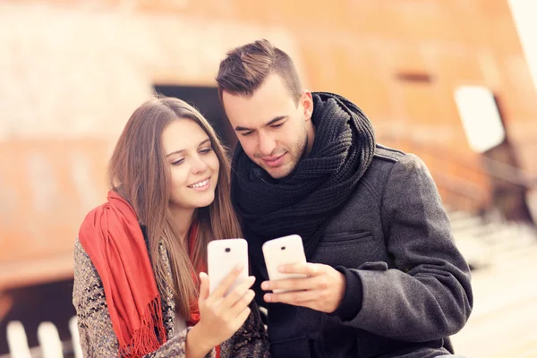 Couple assis sur un banc et utilisant des smartphones — Photo