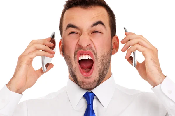 Angry businessman talking on two phones — Stock Photo, Image