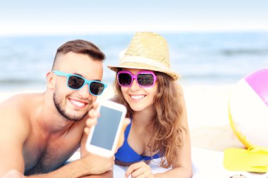 Mutlu çift gösteren smartphone sahilde