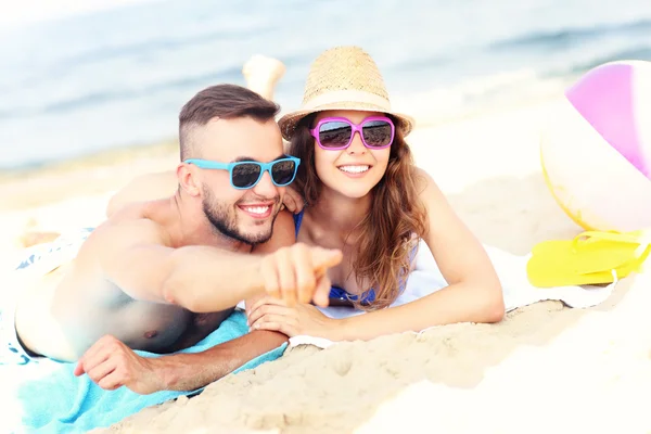 Casal feliz apontando para algo na praia — Fotografia de Stock
