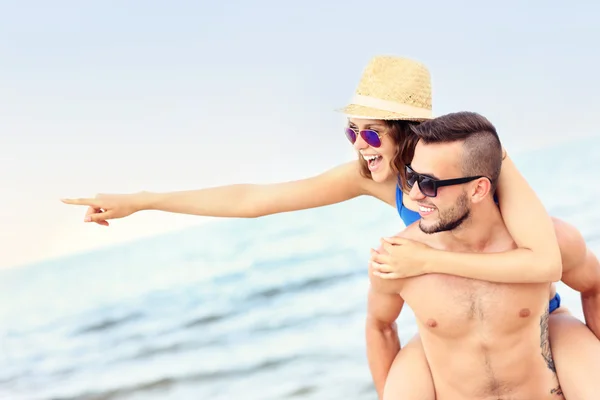 Ungt par pekar på något på stranden — Stockfoto