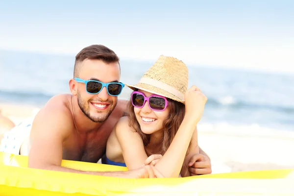 Casal jovem banhos de sol na praia — Fotografia de Stock