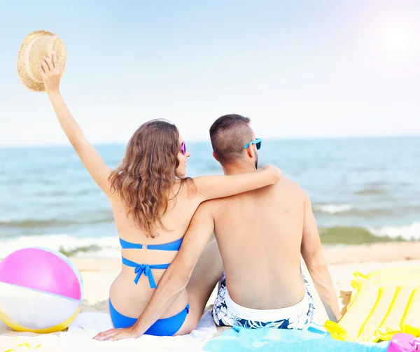 Jeune couple assis sur la plage — Photo