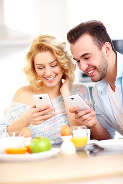 Casal feliz usando telefones inteligentes — Fotografia de Stock