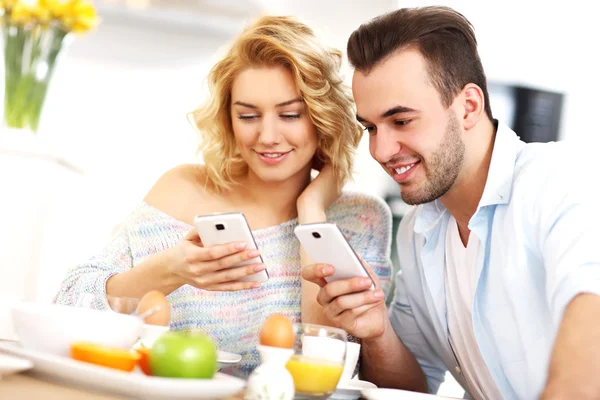 Pareja feliz usando teléfonos inteligentes — Foto de Stock