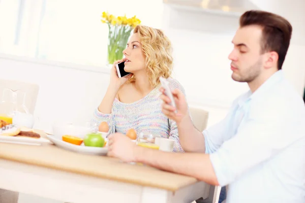 Pareja feliz usando teléfonos inteligentes — Foto de Stock