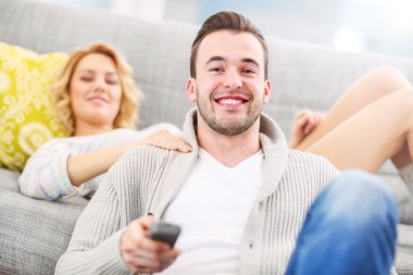 Mutlu çift evde televizyon izliyor.