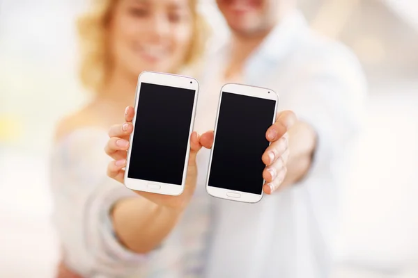 Pareja mostrando sus teléfonos inteligentes — Foto de Stock