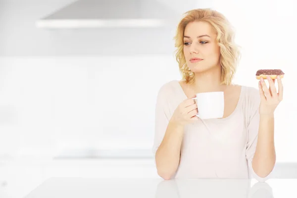 Junge Frau isst Donut mit Kaffee — Stockfoto