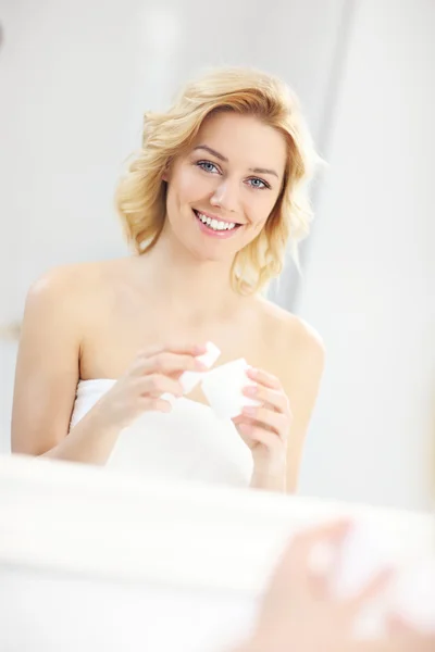 Женщина кладет крем в ванной комнате — стоковое фото