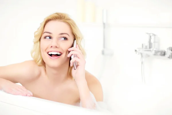 Woman talking on phone in bath — Stock Photo, Image