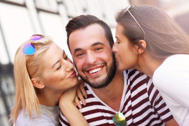 İki kadın bir erkeği öpüyor.