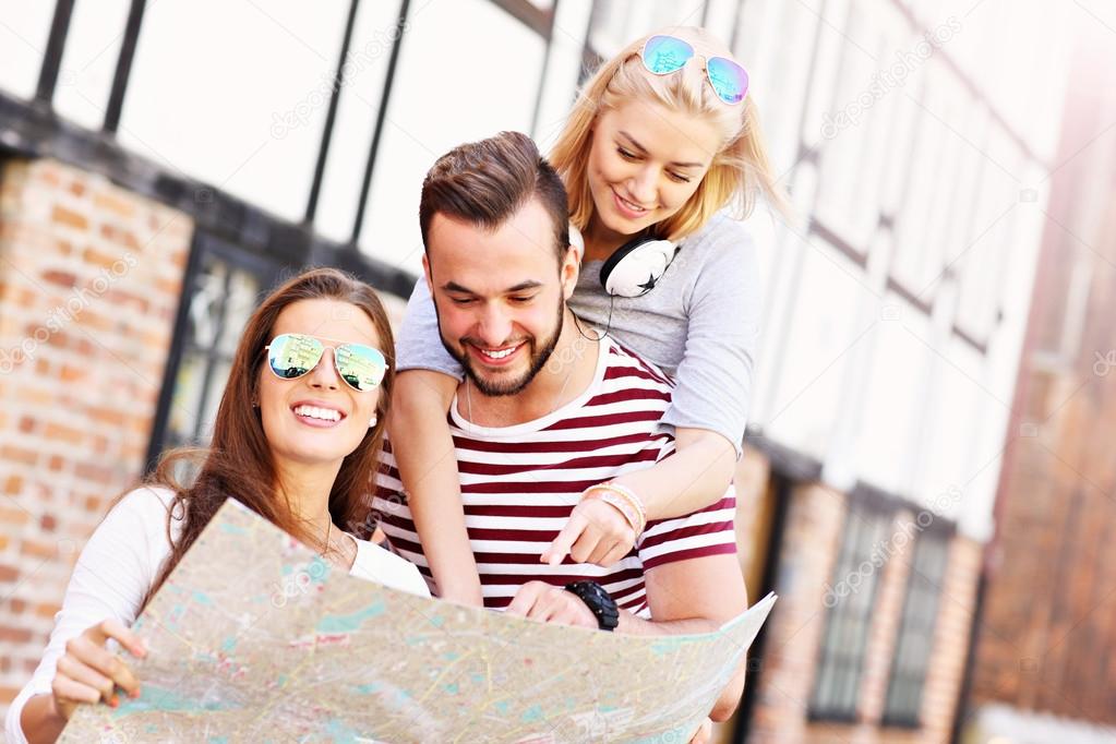 Happy friends sightseeing with map