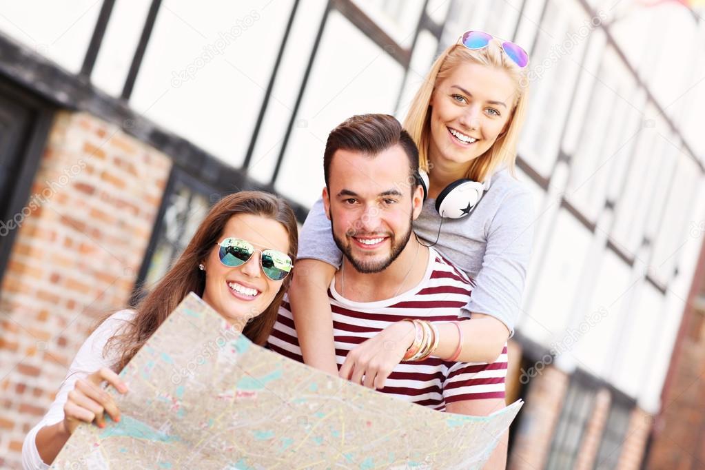 Happy friends sightseeing with map