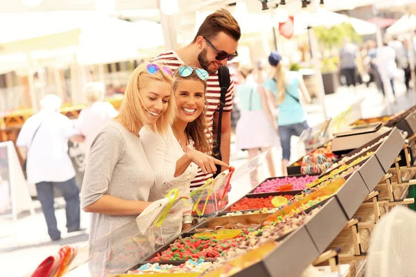 Friends buying jelly sweets on market — Stock Photo, Image