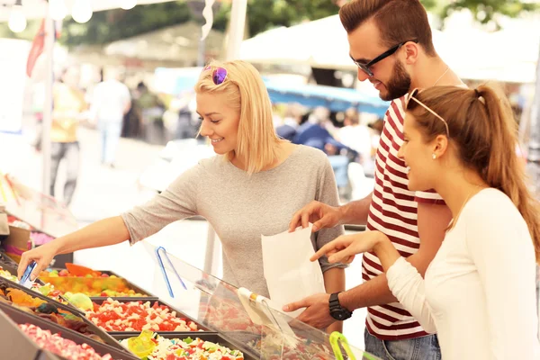 Friends buying jelly sweets on market — Stock Photo, Image