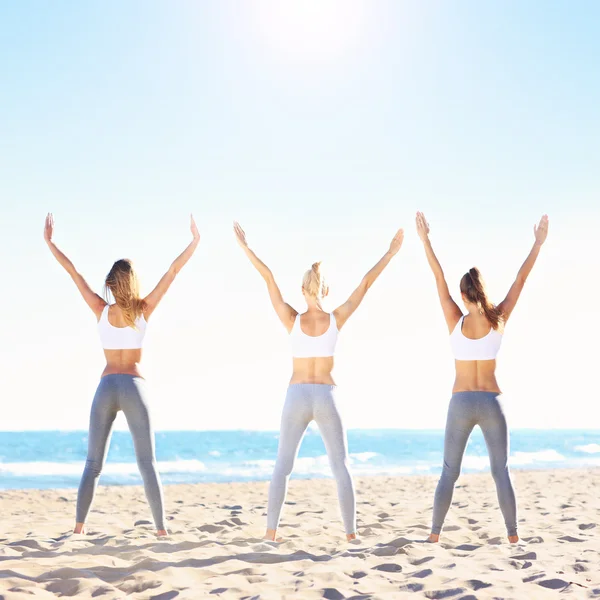 Groupe de femmes pratiquant le yoga sur la plage — Photo