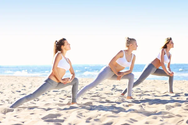 Grupp kvinnor som utövar yoga på stranden — Stockfoto