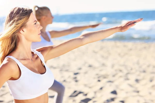 Skupina žen cvičí jógu na pláži — Stock fotografie