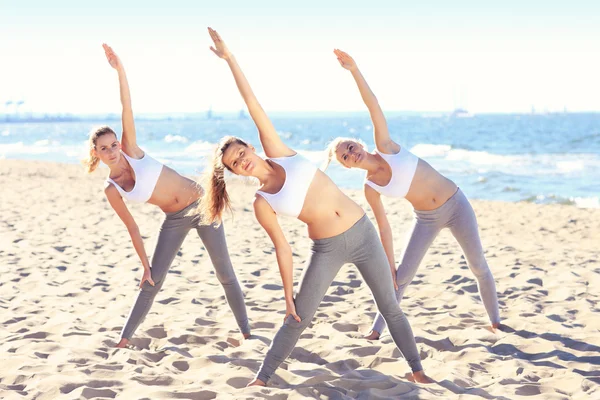 Grupo de mujeres practicando yoga en la playa — Foto de Stock