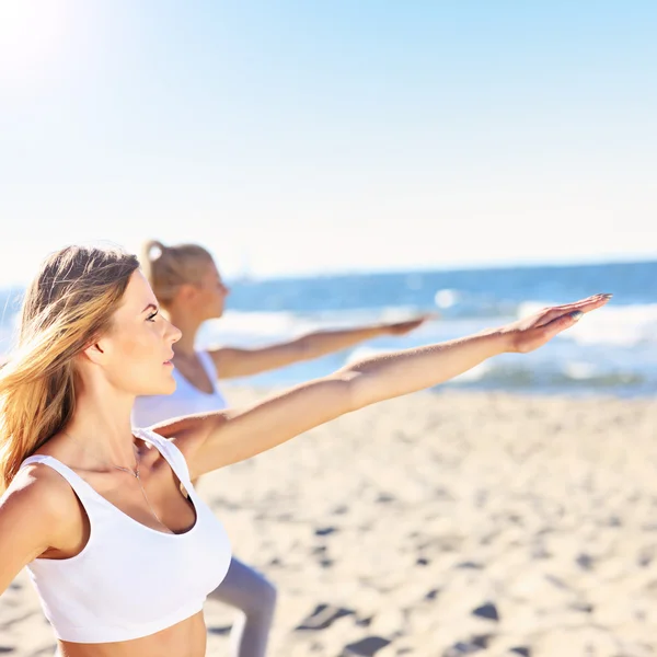 Gruppo di donne che praticano yoga sulla spiaggia — Foto Stock