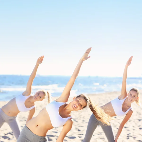 Group of women practicing yoga on the beach — Stock Photo, Image
