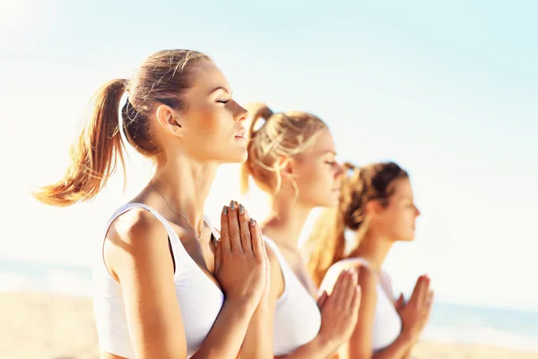 Grupp kvinnor som utövar yoga på stranden — Stockfoto