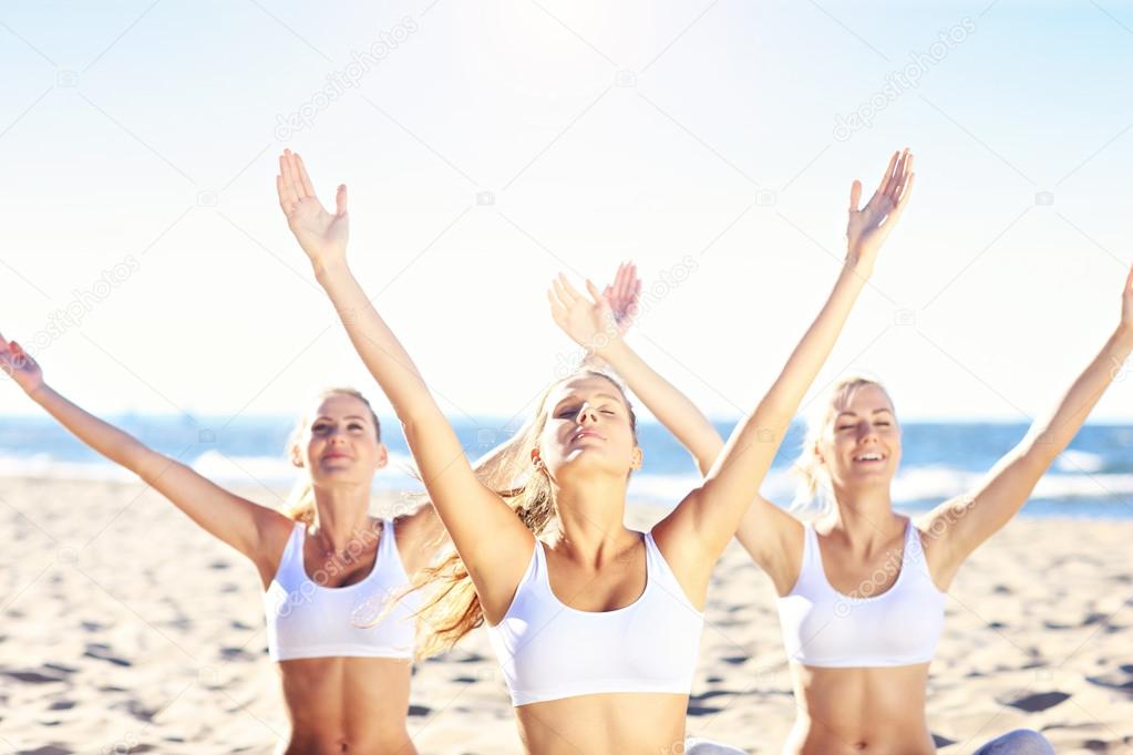 Group of women practicing yoga on the beach