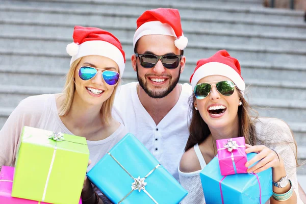 Group of friends in Santa's hats with presents — Stock Photo, Image