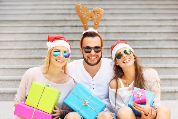 Group of friends in Santa's hats with presents — Stock Photo, Image