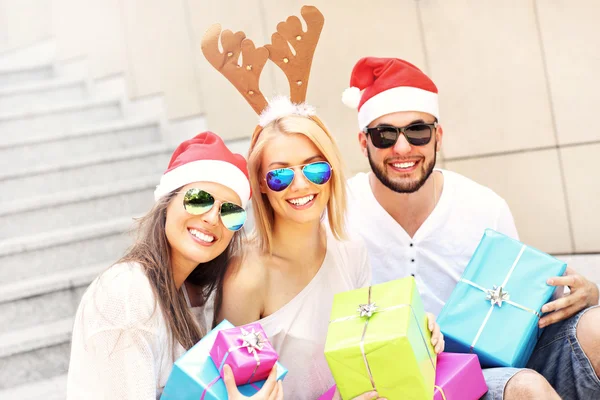 Group of friends in Santa's hats with presents — Stock Photo, Image