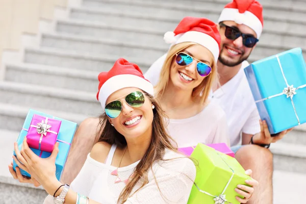 Gruppe von Freunden in Weihnachtsmannmützen mit Geschenken — Stockfoto