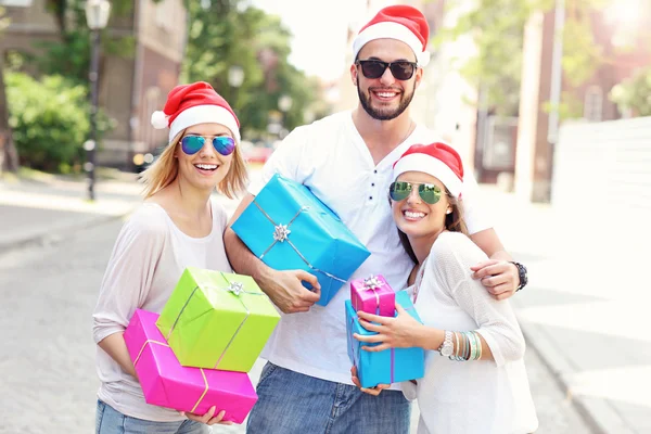 Gruppe von Freunden in Weihnachtsmannmützen mit Geschenken — Stockfoto