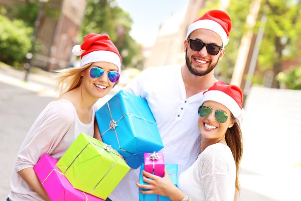 Group of friends in Santa's hats with presents — Stock Photo, Image