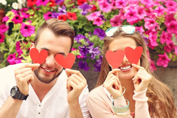 Romantic couple covering eyes with hearts — Stock Photo, Image